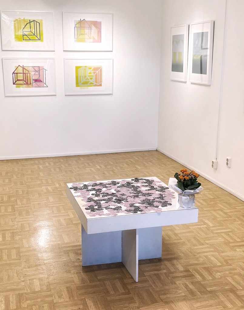 Kaksi naista keskustelee, taustalla tauluja